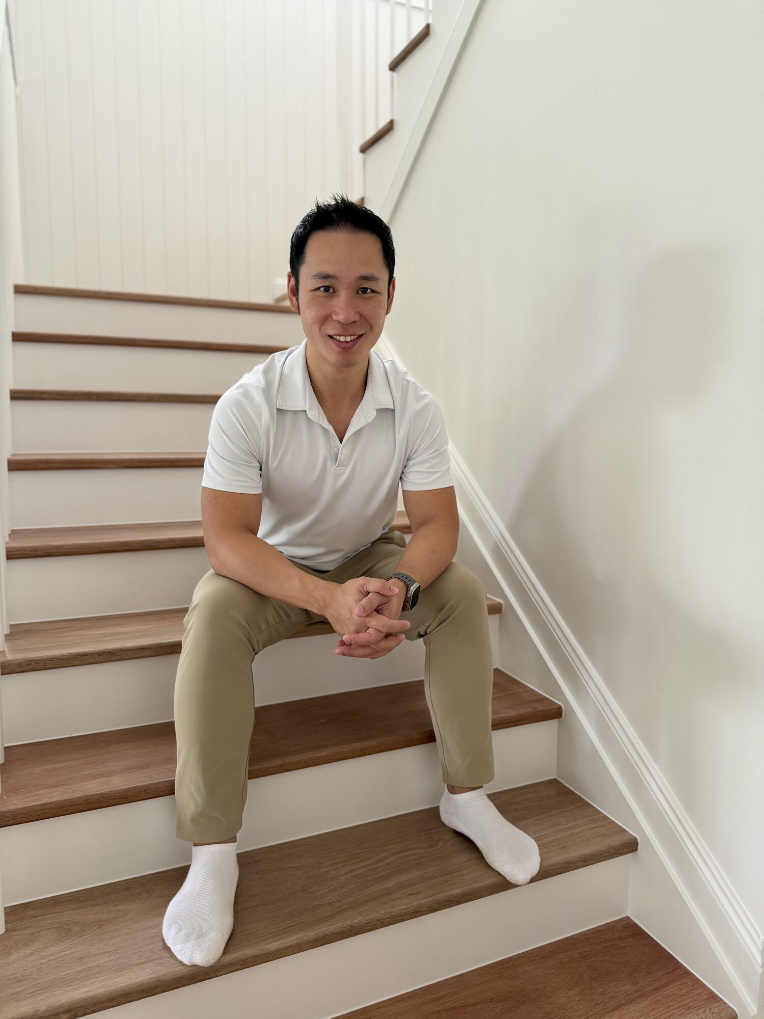 Ian Chan, founder of Imperial Acquisitions Network, seated on a timber staircase