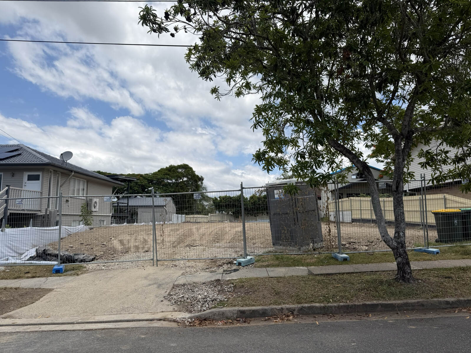 Vacant cleared development site behind temporary fencing on a Brisbane street