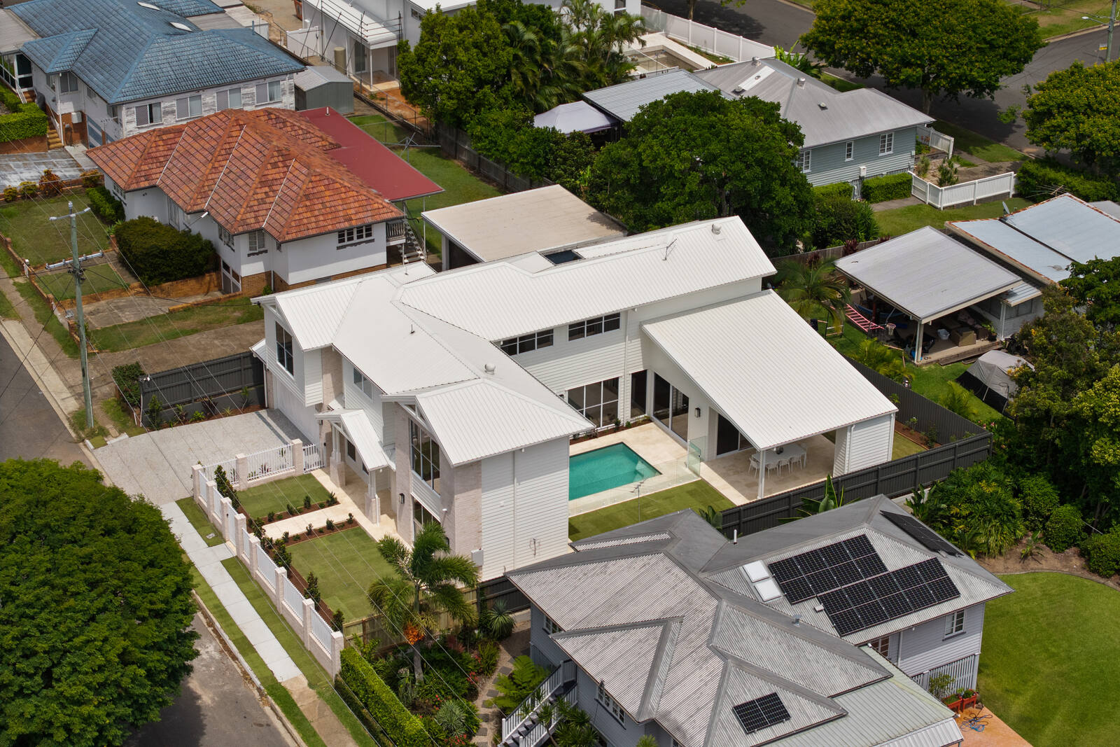 Aerial view of a completed two-storey home with a pool among established Brisbane houses