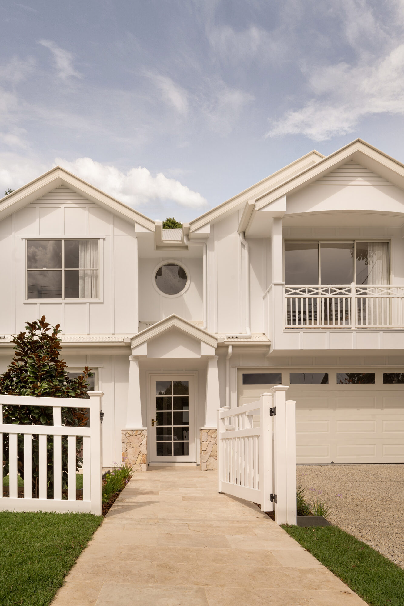 Two-storey white Hamptons-style home with a double garage and picket fence, Brisbane