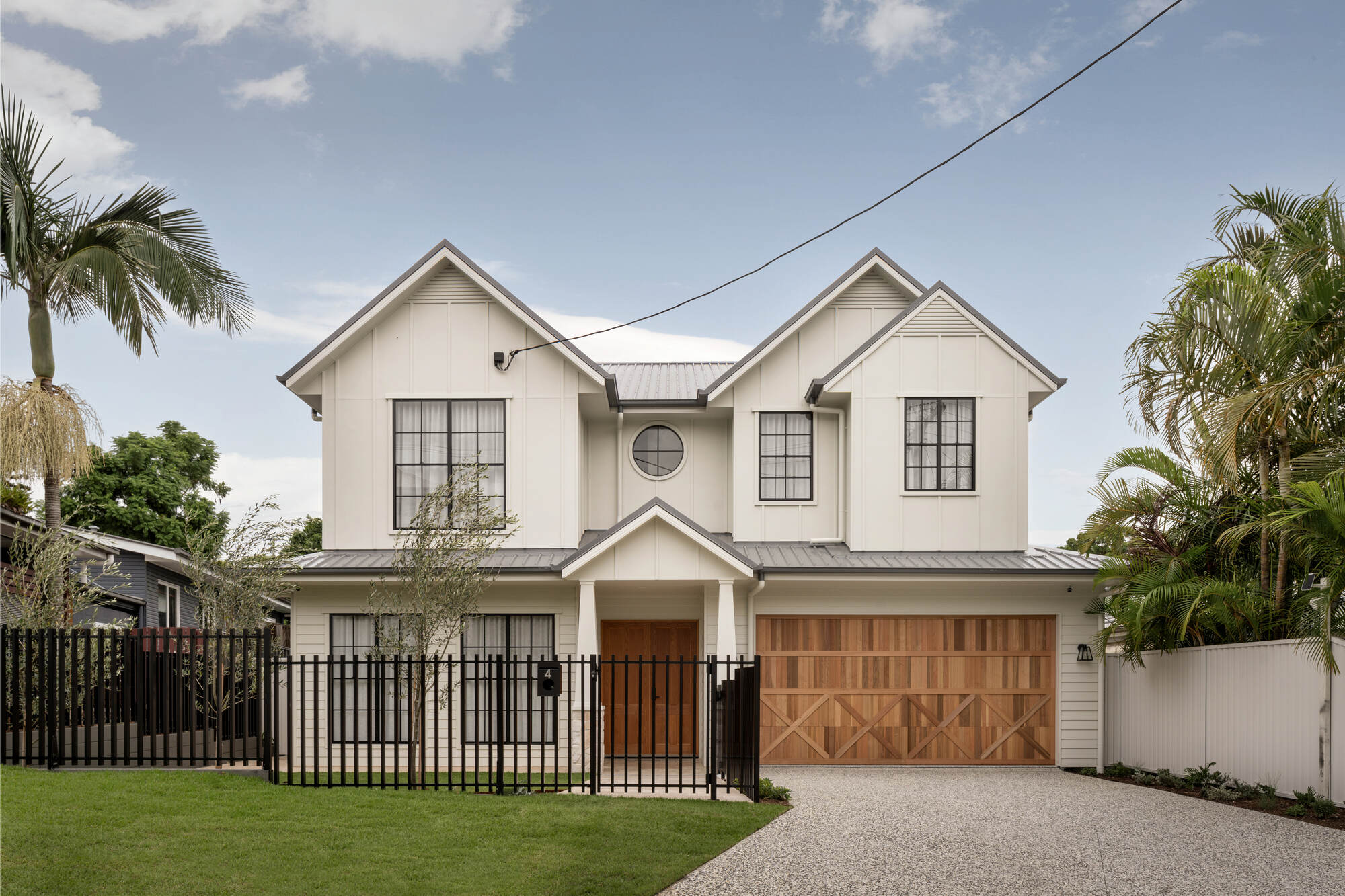 Two-storey contemporary home with a timber double garage and black steel fence, Brisbane
