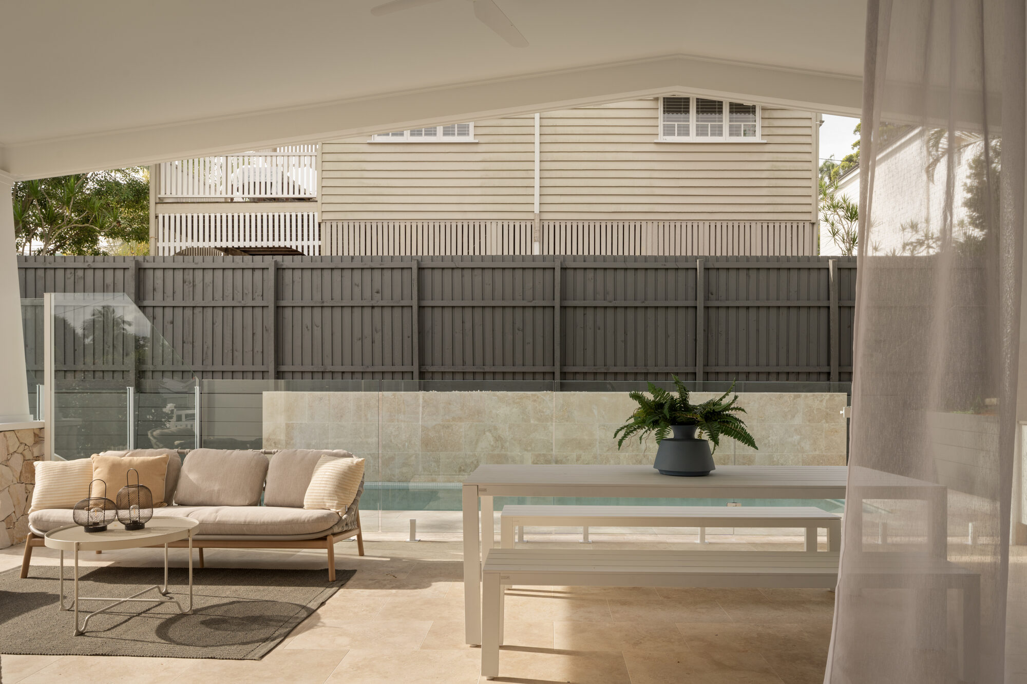 Covered alfresco area with lounge seating beside a pool at a premium Brisbane home