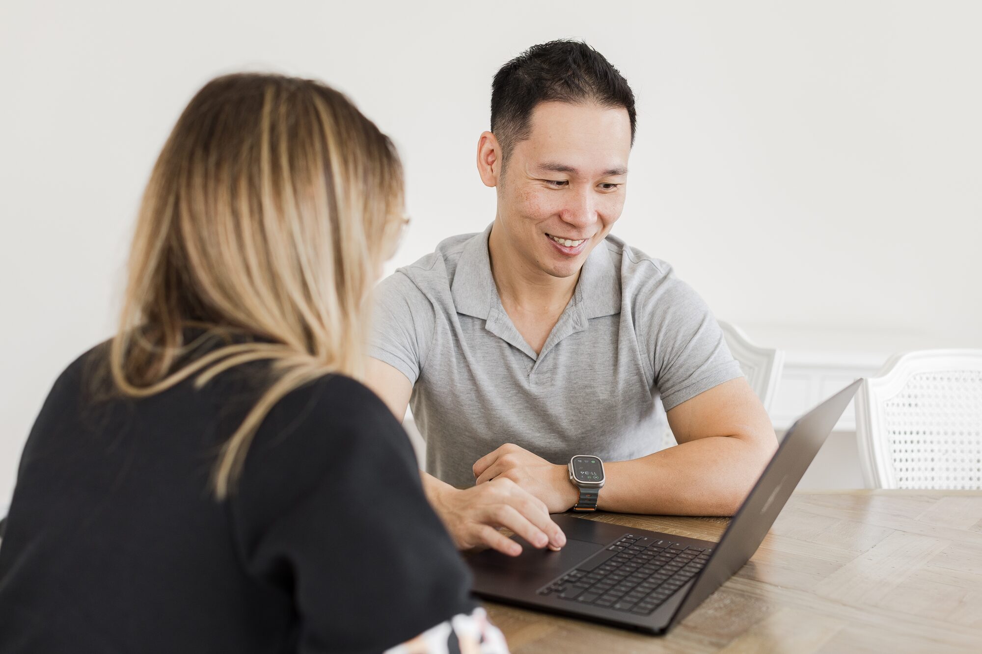 Ian Chan going through options on a laptop with a client at a dining table