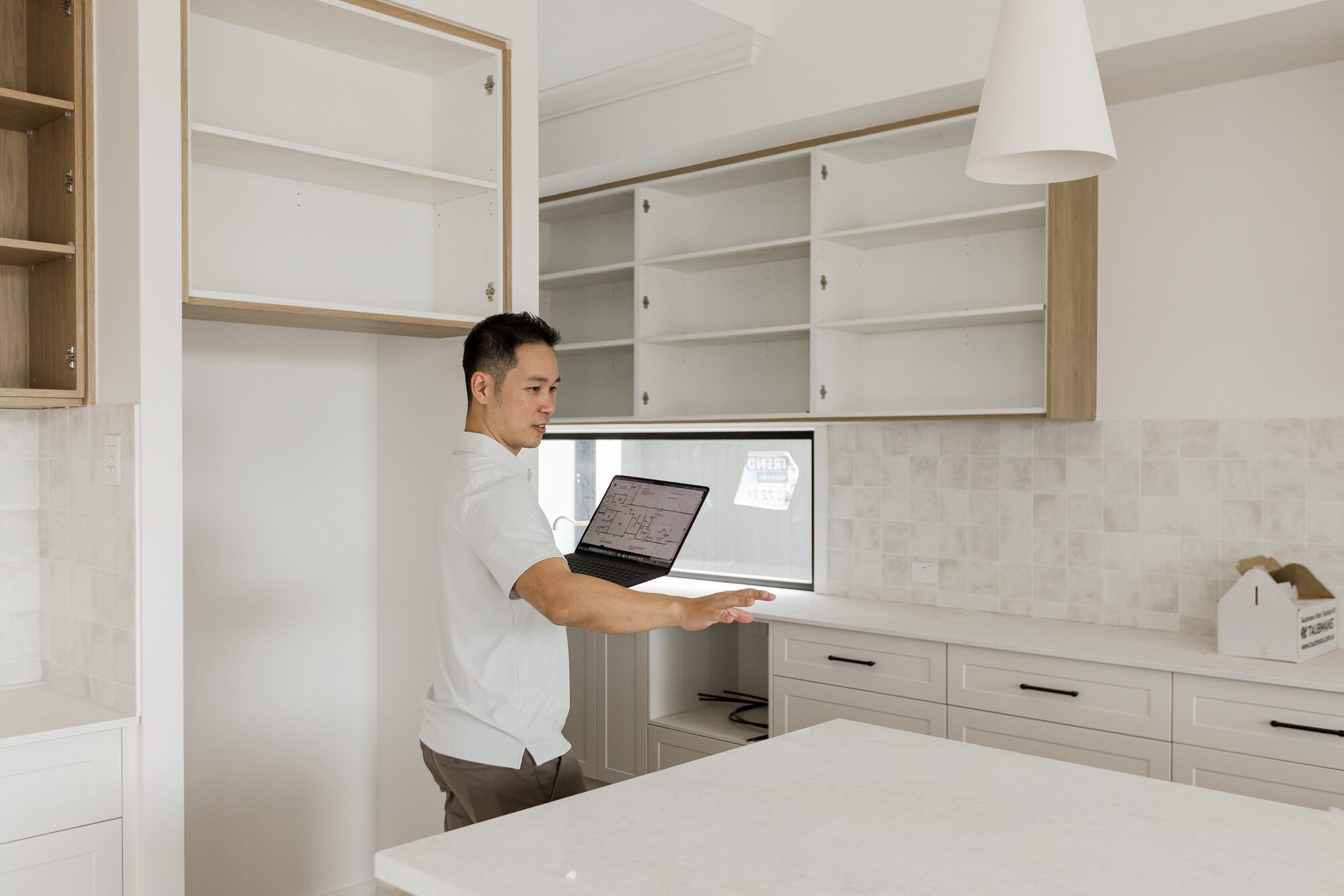 Ian Chan reviewing plans on a laptop in a kitchen nearing completion