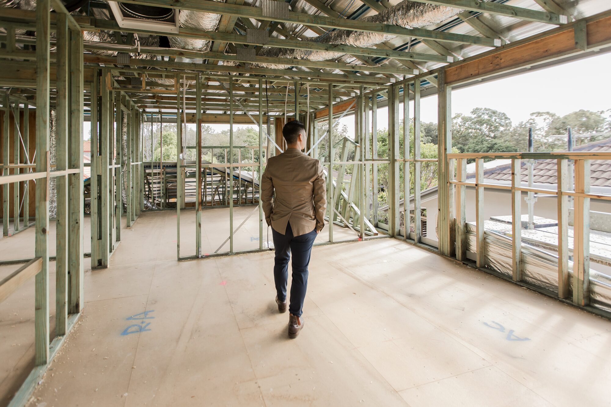Ian Chan walking through the timber and steel frame of a house under construction