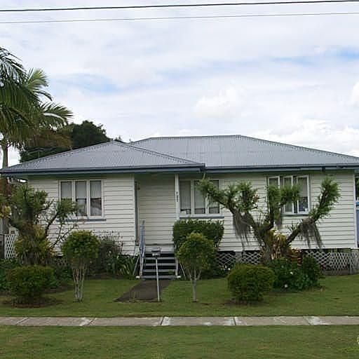 Single-storey weatherboard home with a grey roof and established palms, Wynnum